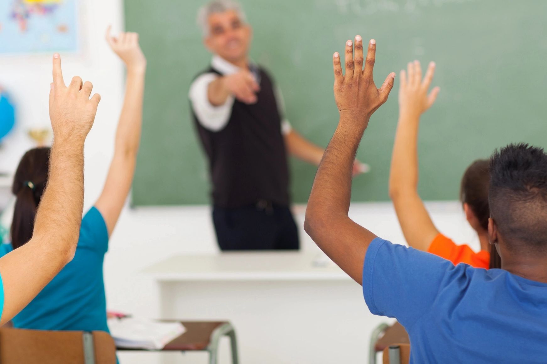 dynamic classroom with students raising hands in active participation viewed from the back