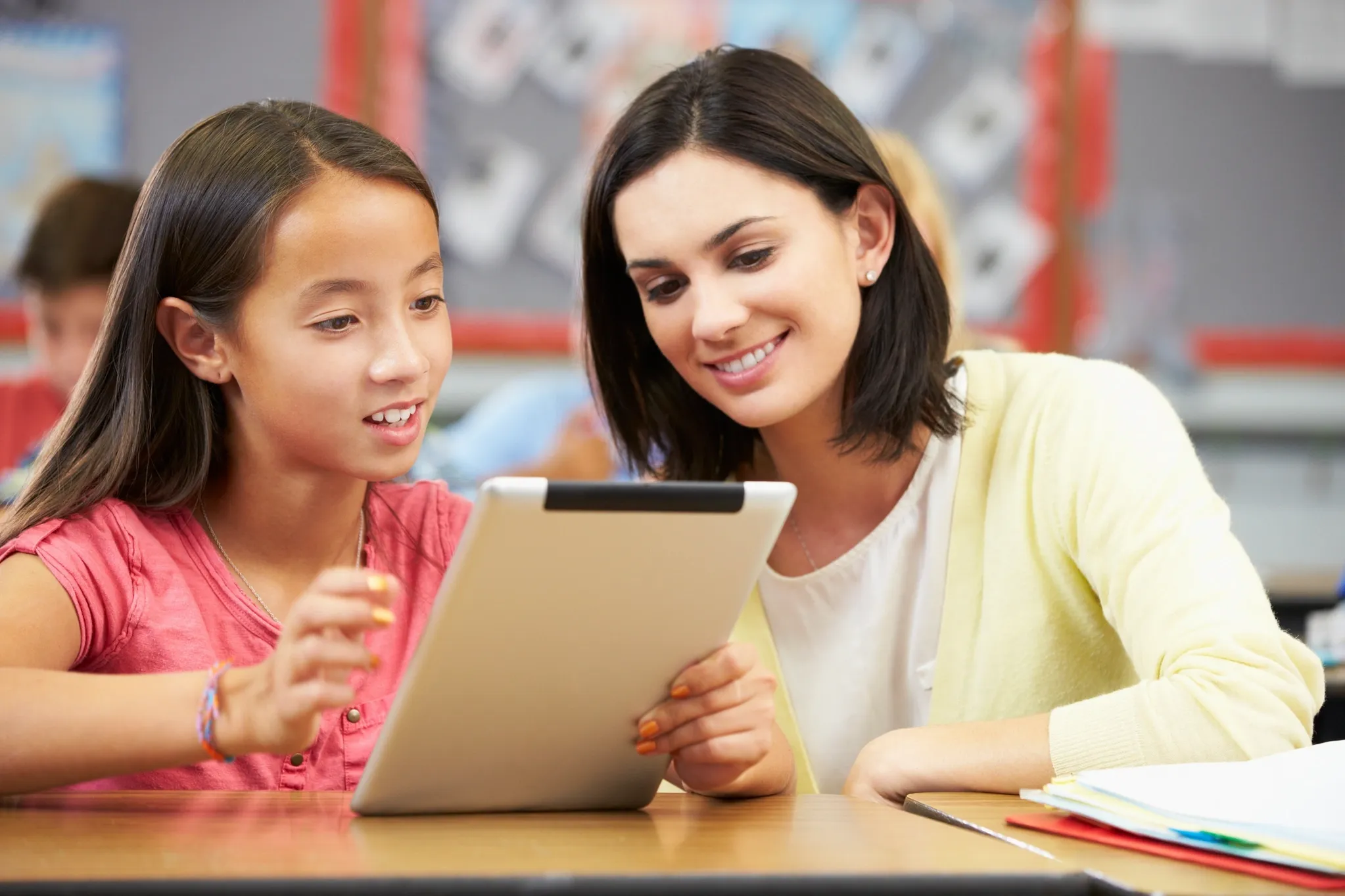 one-on-one learning session of a student with her teacher looking together at a tablet