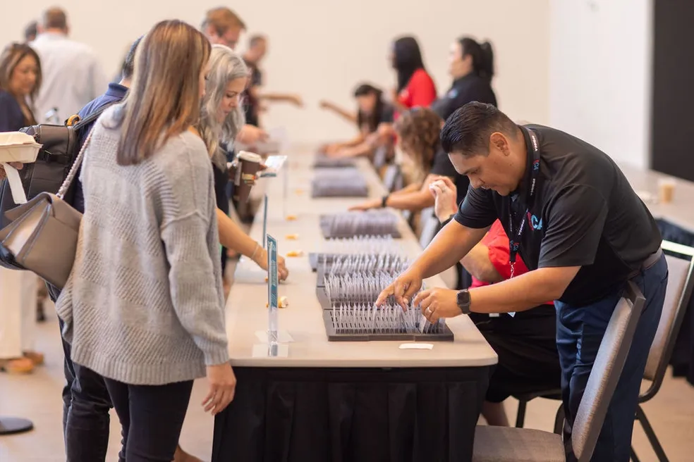 Event staff assisting participants as they pick up name badges and materials
