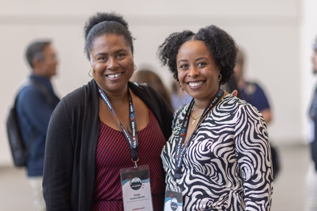 two women stand side by side smiling at camera