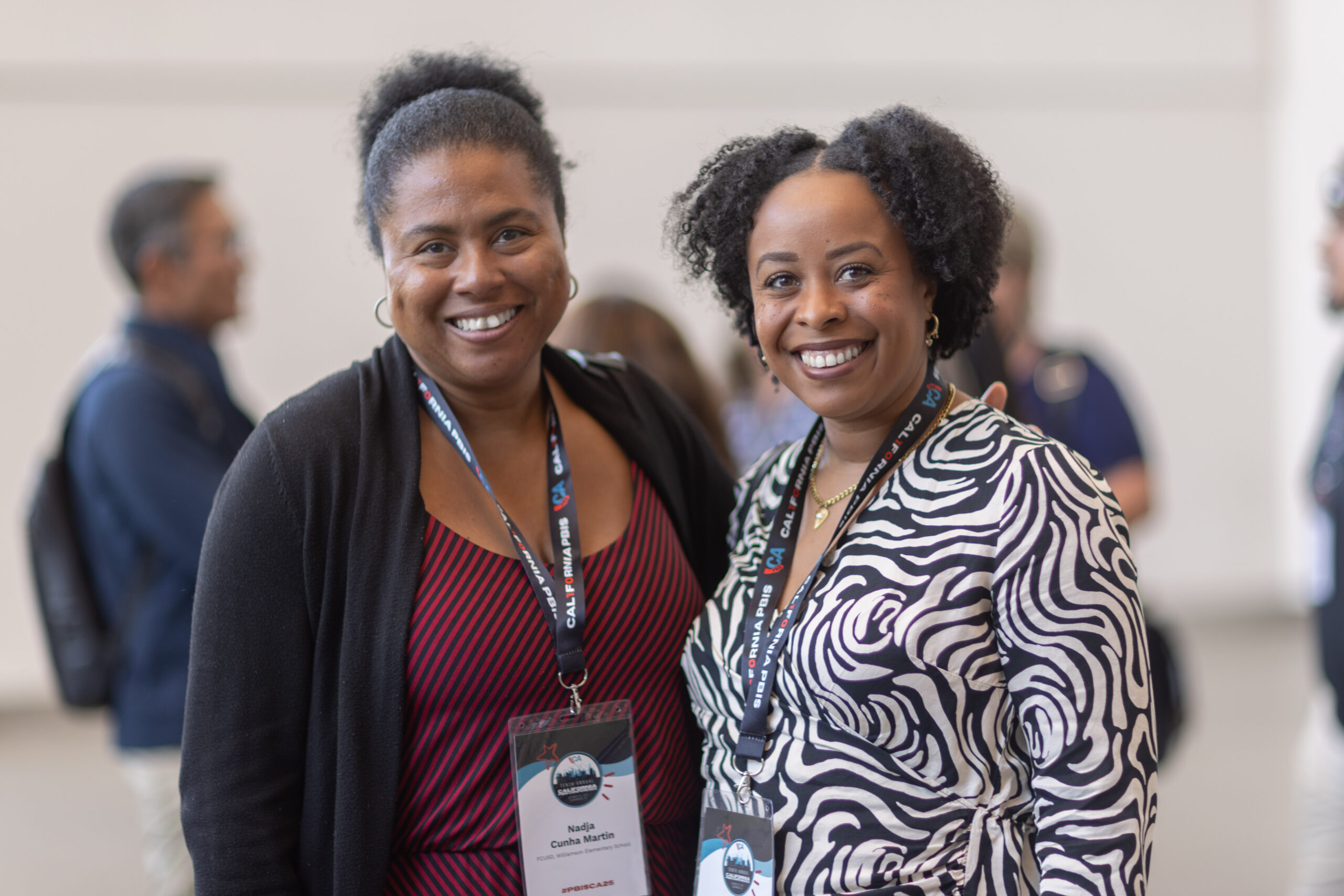 two women stand side by side smiling at camera