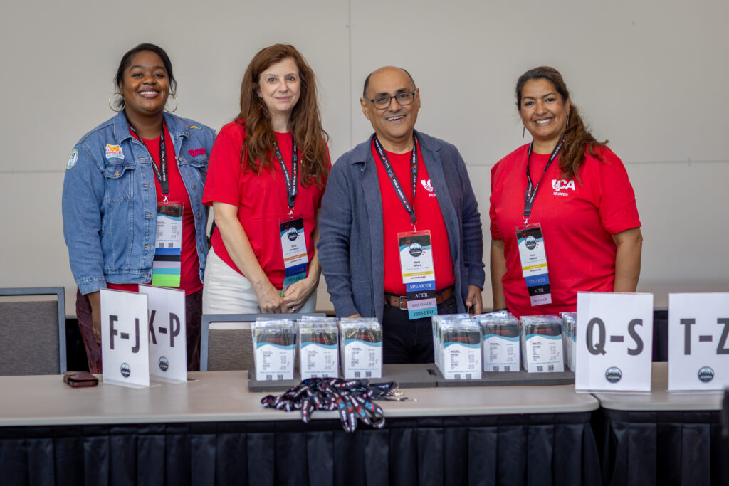 4 event staff stand behind check in table smiling at camera