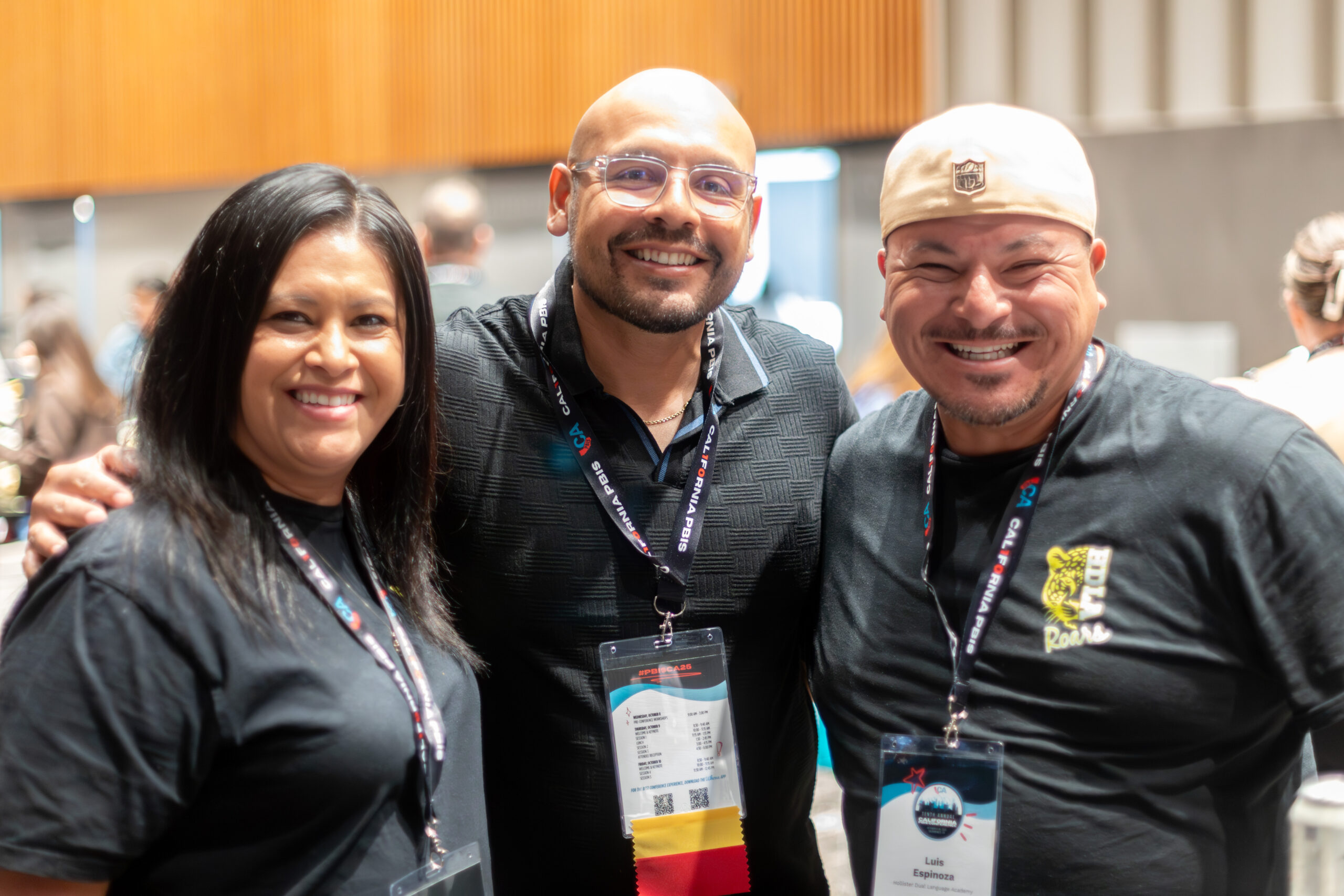 three people stand side by side and smile at camera